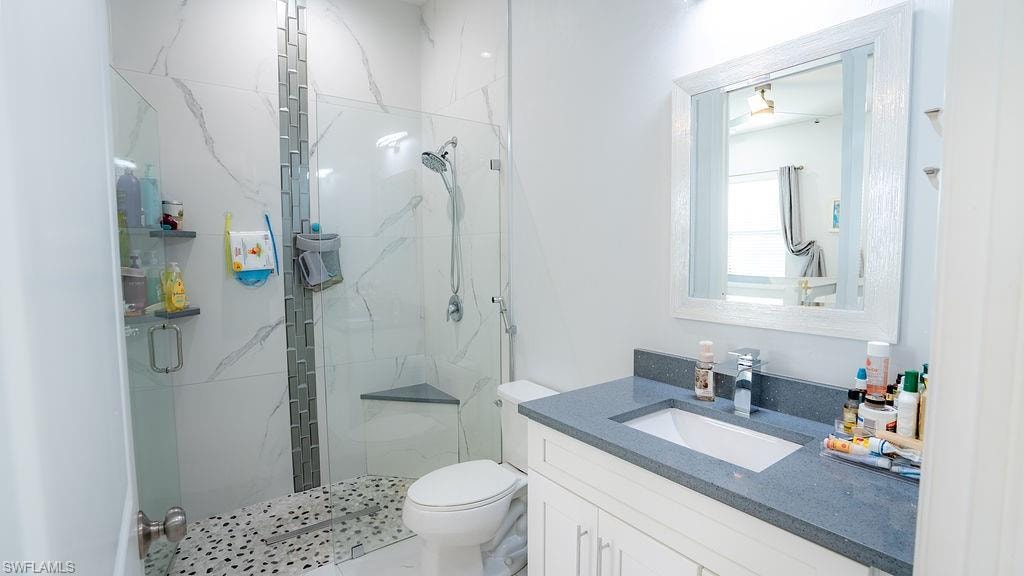 Contemporary bathroom featuring a frameless glass shower enclosure with white marbled tile and a decorative tile accent strip