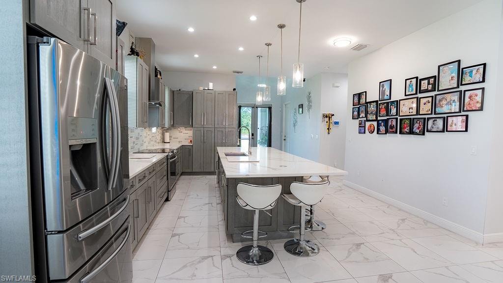 Modern kitchen featuring gray cabinetry, stainless steel appliances, and white stone-finish countertops