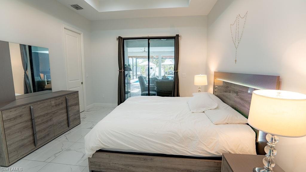 Spacious room featuring large format tile flooring and a tray ceiling