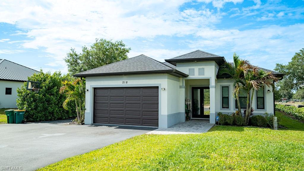 Modern exterior with a two-car garage, paved driveway, and established landscaping