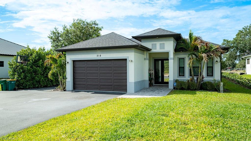 Contemporary stucco exterior featuring a two-car garage, paved driveway, and established landscaping