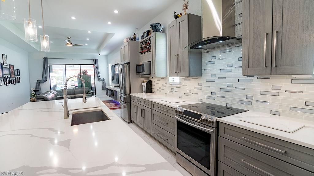 Contemporary kitchen featuring an expansive island with an undermount sink and two pendant lights