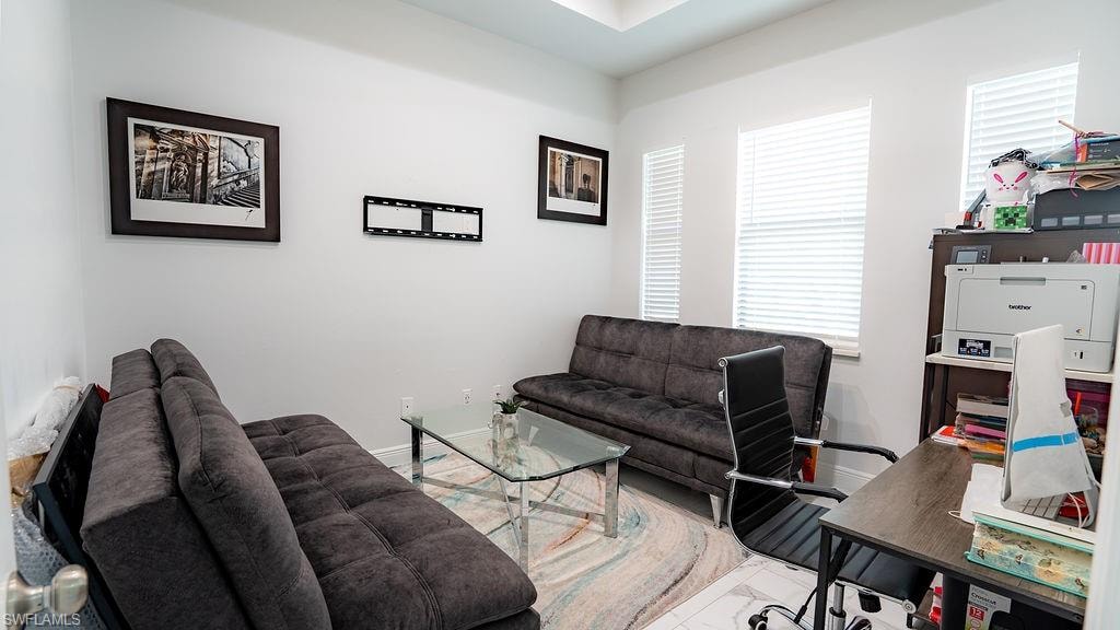 Room featuring multiple windows with blinds, white walls, and a tray ceiling
