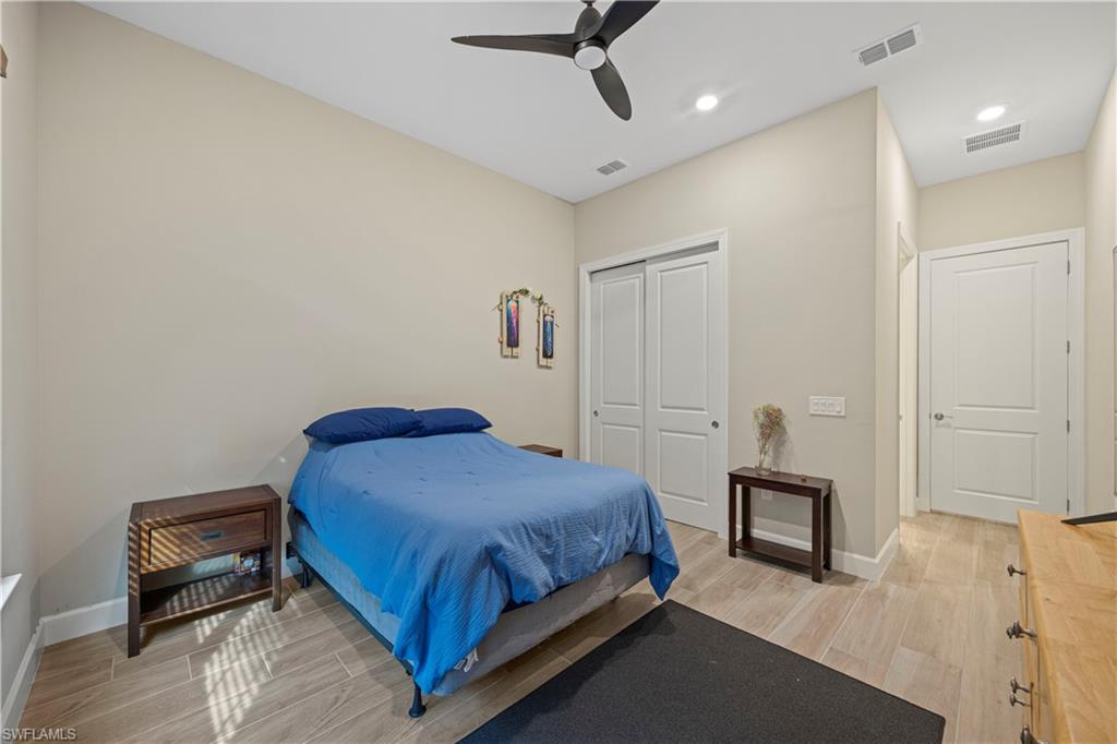 Bedroom with wood tiled floors, a closet, ceiling fan, and recessed lighting