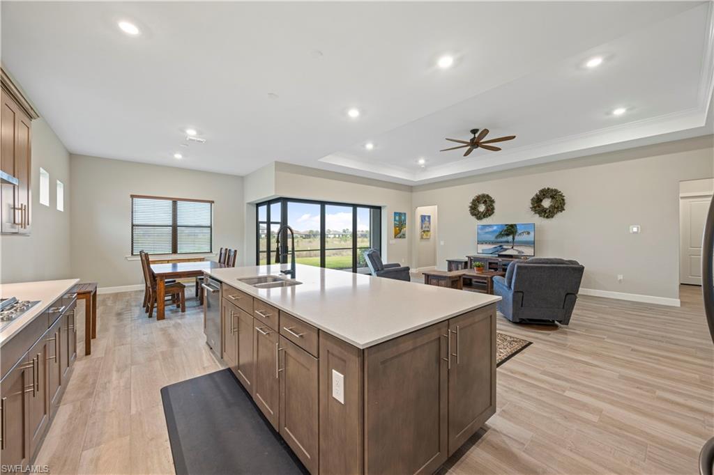 Kitchen featuring open floor plan, light wood-type flooring, recessed lighting, an island with sink, and light stone countertops