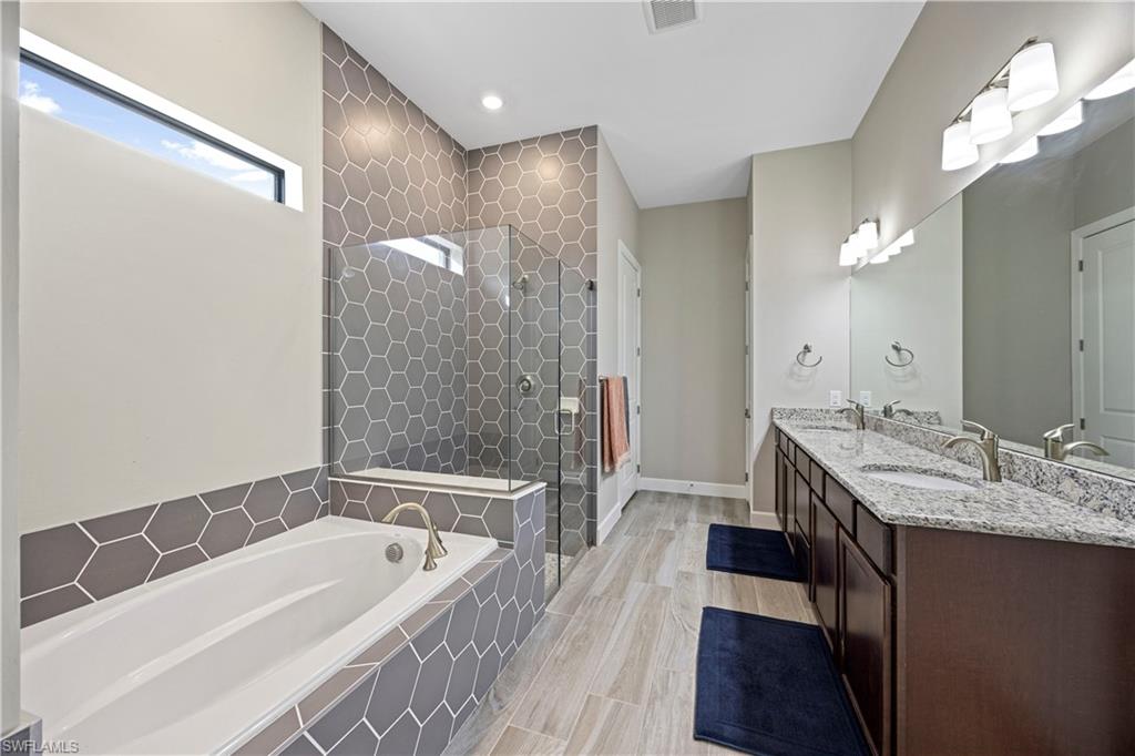 Bathroom with double vanity, a stall shower, a garden tub, and recessed lighting