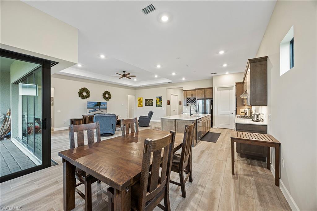 Dining area with a tray ceiling, recessed lighting, light wood-style flooring, and ceiling fan