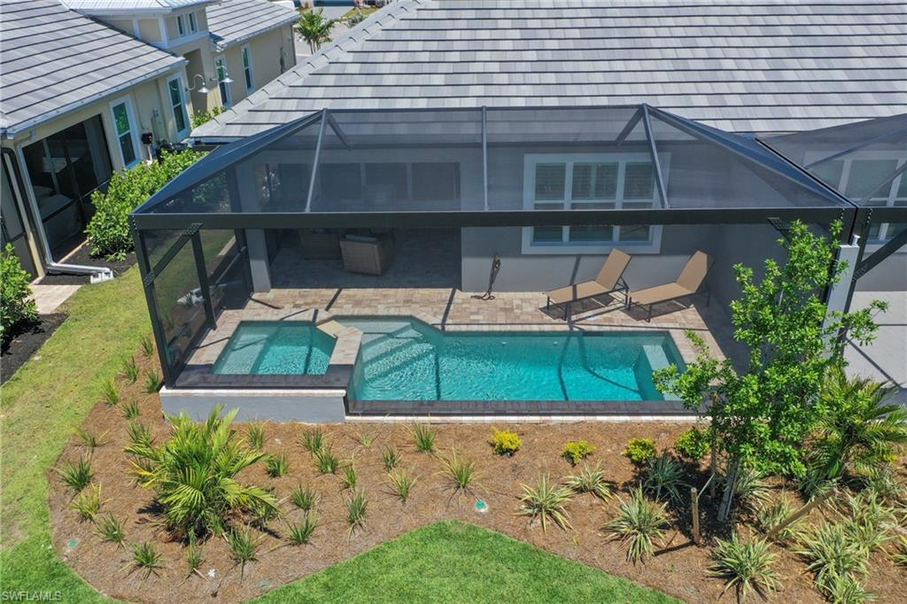Screened patio featuring a swimming pool, integrated spa, and brick paver decking