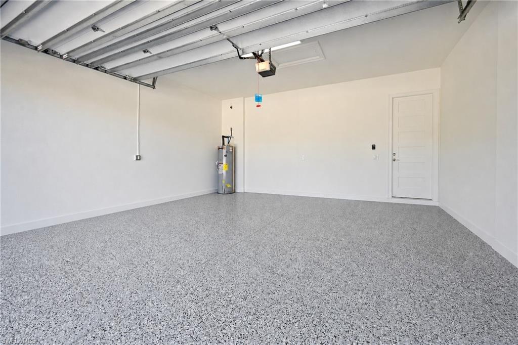 Spacious garage featuring a durable epoxy-coated floor, painted white walls, interior access door, and an overhead garage door opener
