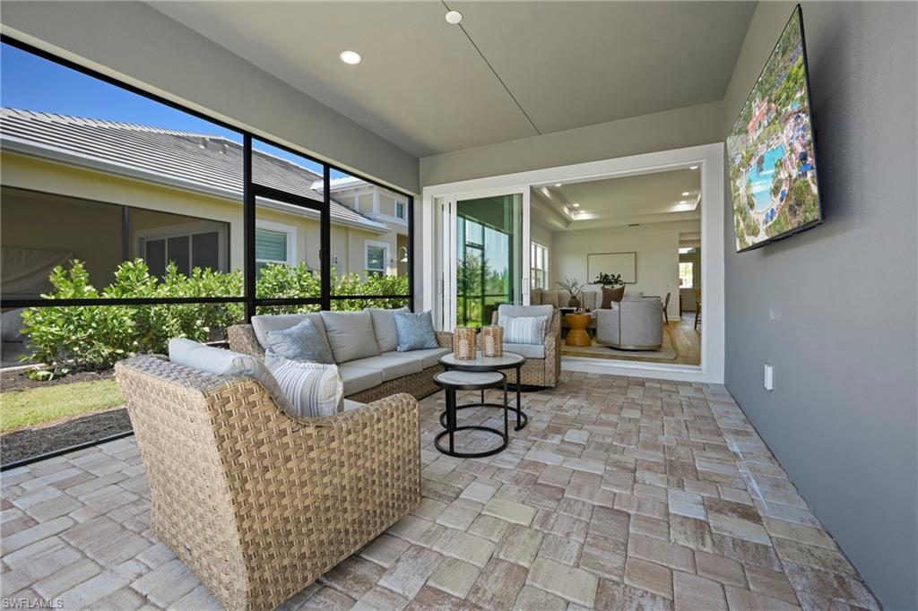 Screened lanai featuring multi-tone paver flooring, a flat ceiling with recessed lighting, and direct access to interior living spaces via sliding glass doors