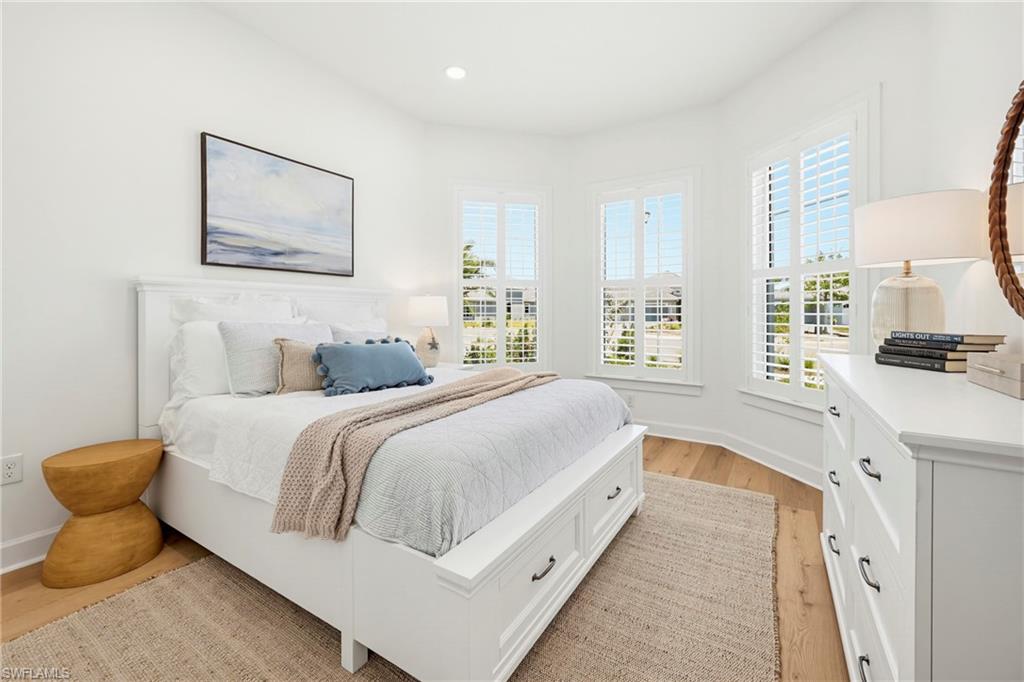 Bright room featuring light wood-finish flooring, white walls, and recessed lighting