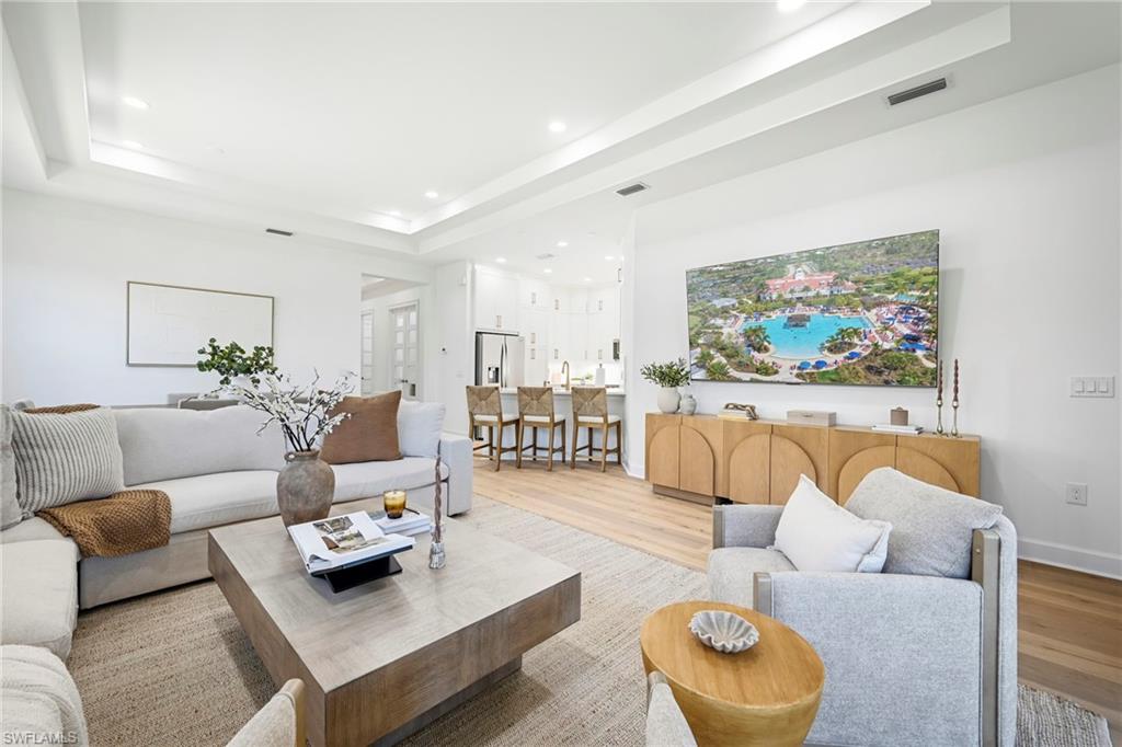 Spacious living area featuring light wood-finish flooring, recessed lighting, and a tray ceiling