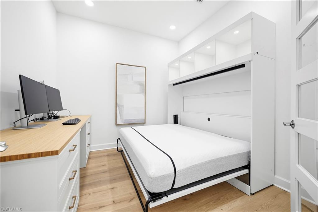 Integrated white Murphy bed with upper illuminated shelving