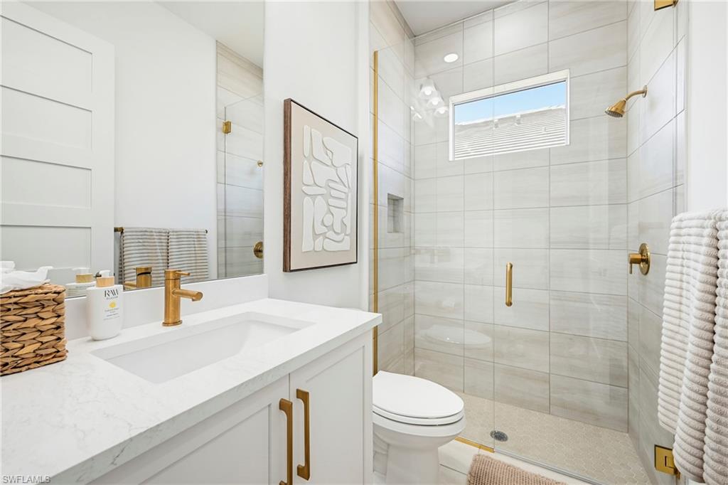Contemporary bathroom featuring a frameless glass shower enclosure with brass hardware, a built-in shower niche, and a window for natural light