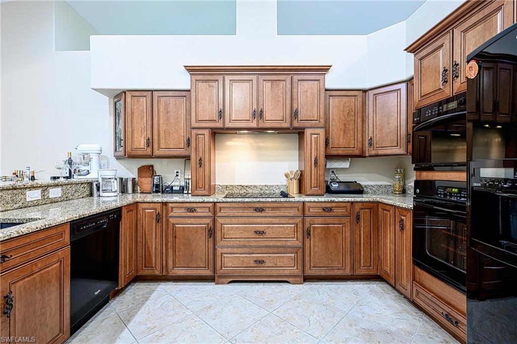 Kitchen featuring light stone counters and black appliances