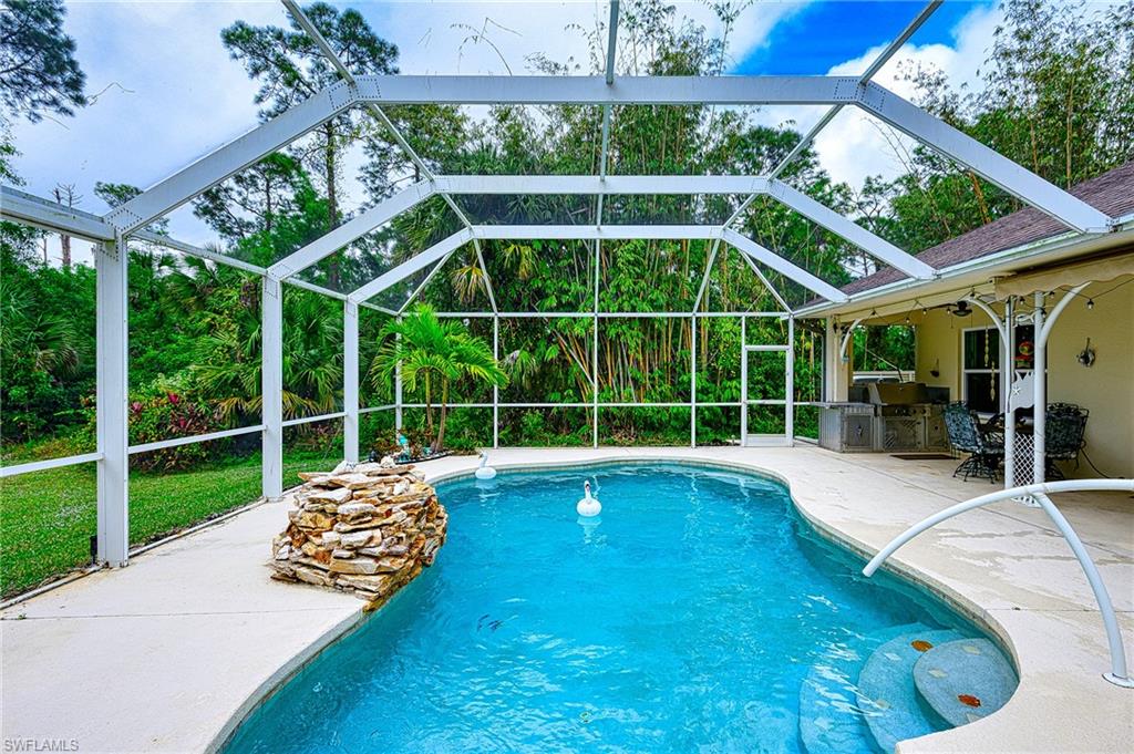 View of swimming pool with a lanai, an outdoor kitchen, and a patio area