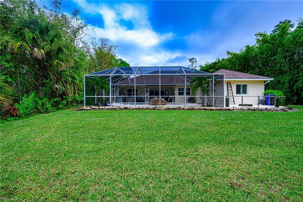 Rear view of property featuring a yard, a patio area, and a lanai.  Fire pit to right after screened area