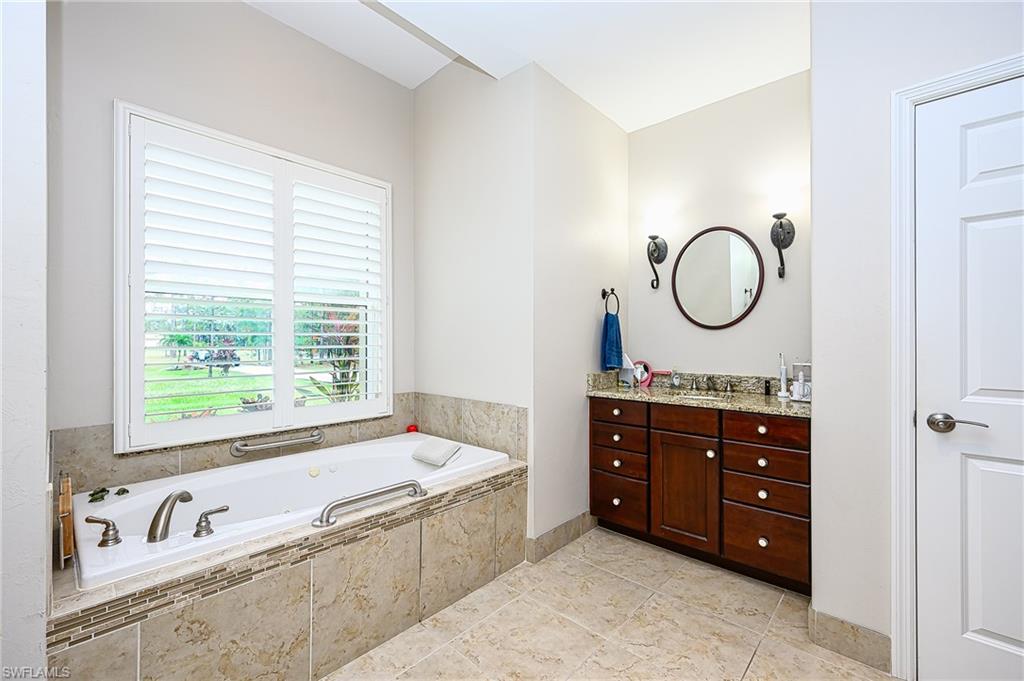 Bathroom featuring tile flooring and vanity and tiled bath