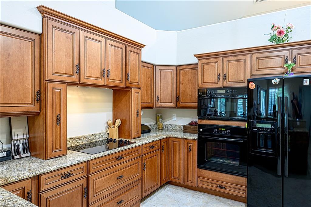 Kitchen with light stone counters and black appliances