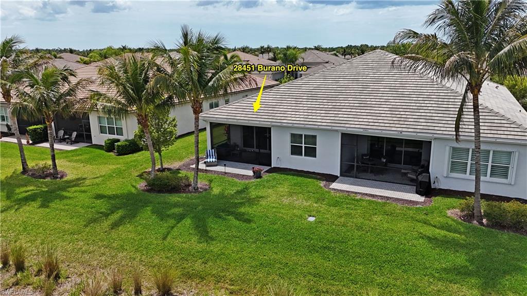 Expansive rear exterior featuring a screened lanai, a large green lawn, and mature palm trees