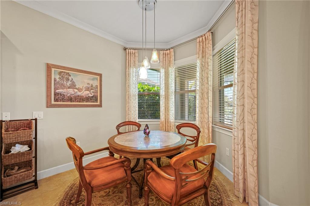 Bay window dining area with crown molding, light-toned walls, tile flooring, and a contemporary pendant light fixture