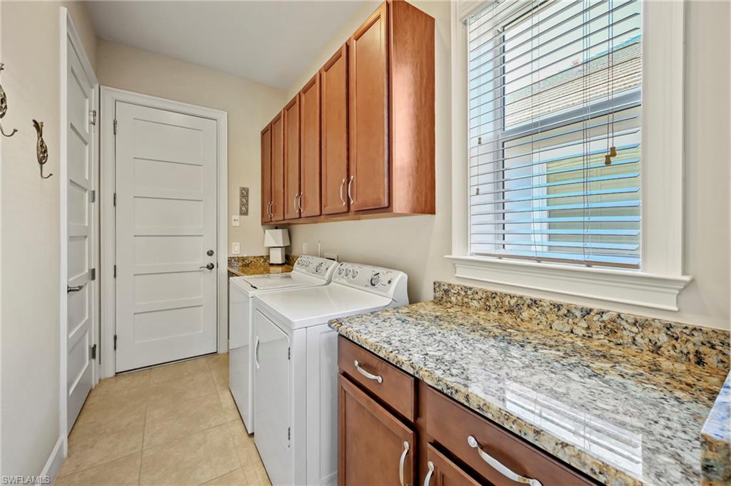 Laundry area featuring a window with blinds, tile flooring, and wood cabinetry