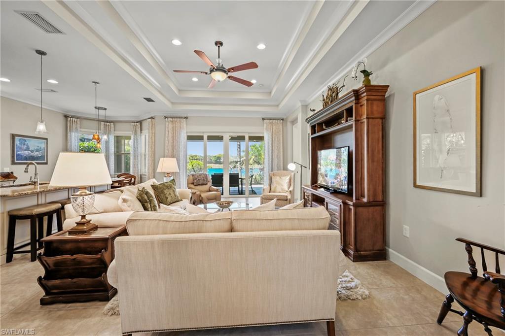 Open-concept living area with tray ceilings and recessed lighting