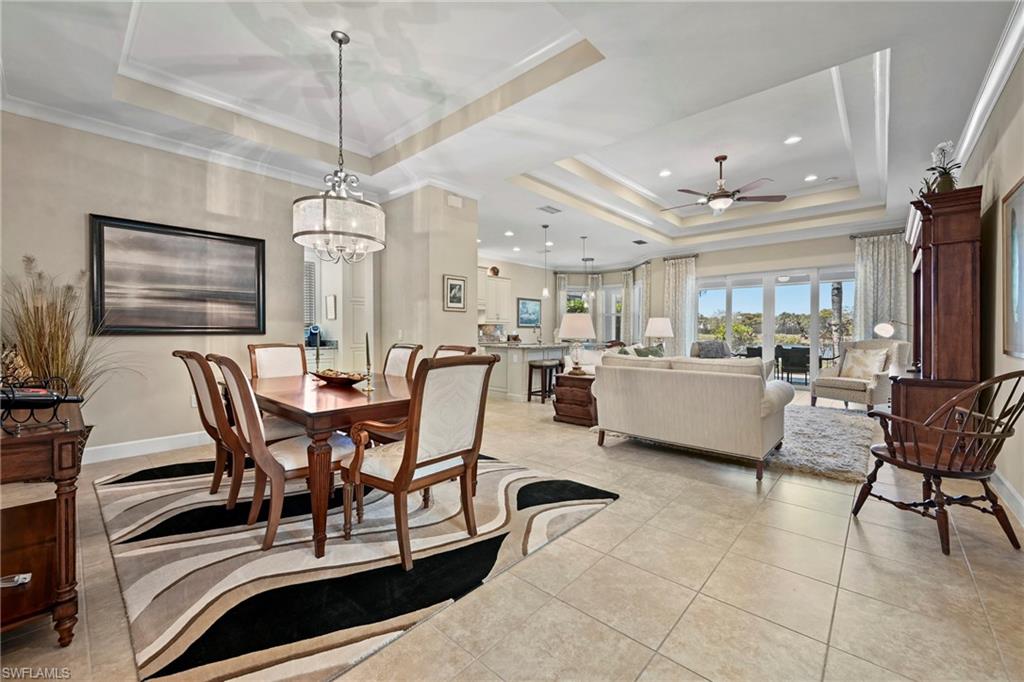 Open-concept living space featuring a tray ceiling, recessed lighting, tile flooring, and sliding glass doors