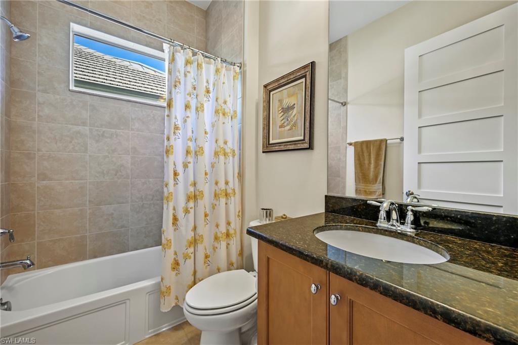 Bathroom featuring a dark speckled countertop vanity with an undermount sink and chrome faucet