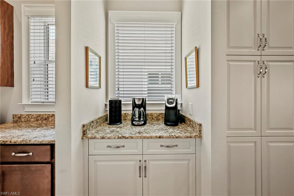 Kitchenette area featuring light-toned countertops, white shaker-style cabinetry, and integrated windows with blinds