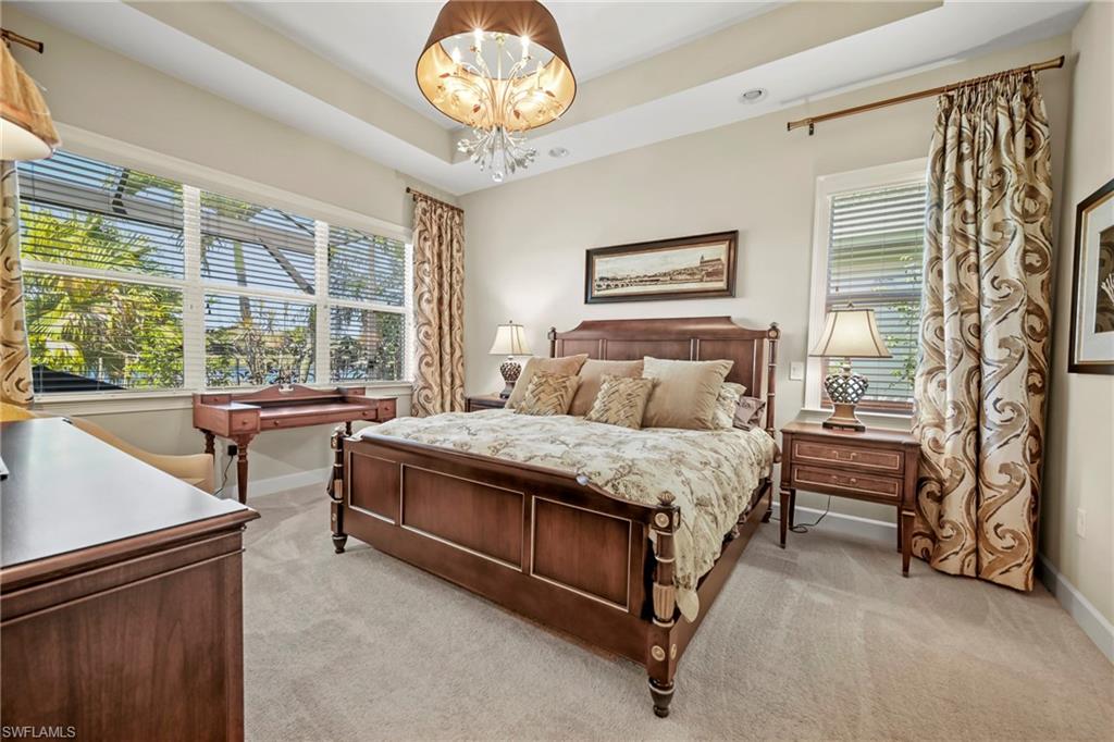 Tray ceiling with chandelier lighting, expansive window with horizontal blinds, neutral carpet flooring, recessed lighting, and wall-mounted picture rail