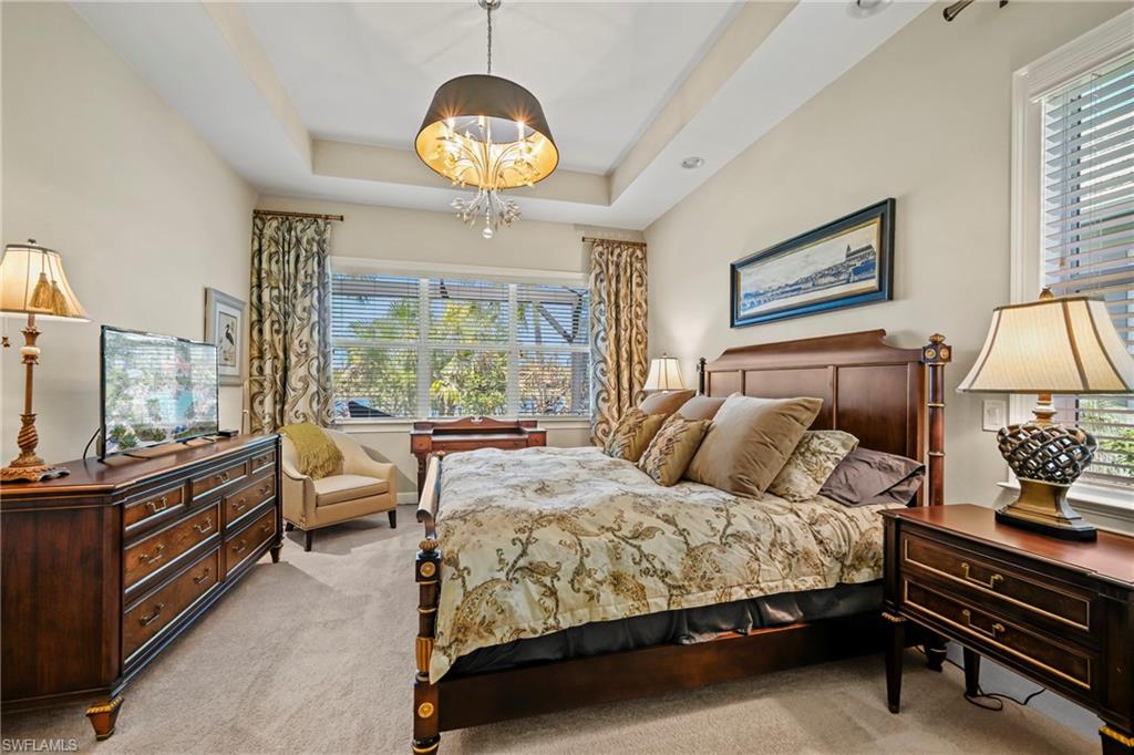 Bedroom featuring neutral wall tones, tray ceiling, and carpeted flooring