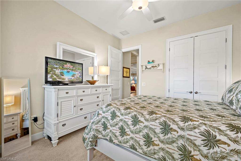 Neutral wall paint with carpet flooring, a ceiling fan with integrated lighting, and a double-door closet with contemporary paneling