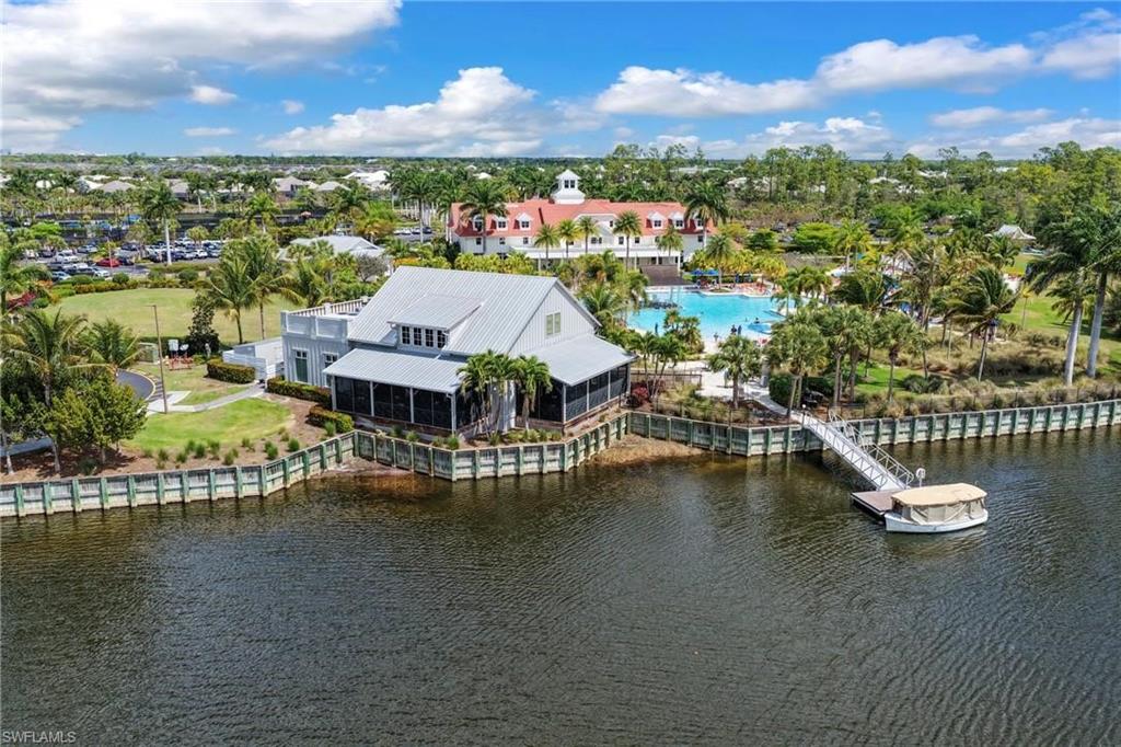 Waterfront property featuring a screened porch, private boat dock, and lush tropical landscaping