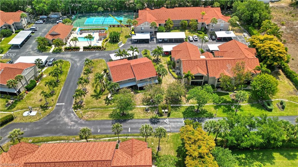 Expansive property featuring multiple buildings with red tile roofs, mature trees, and paved parking areas