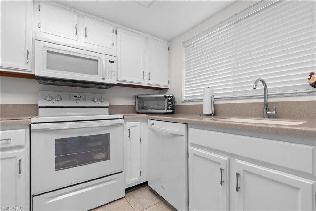 Kitchen featuring white cabinetry, a built-in microwave, an electric range, a dishwasher, and a window with horizontal blinds