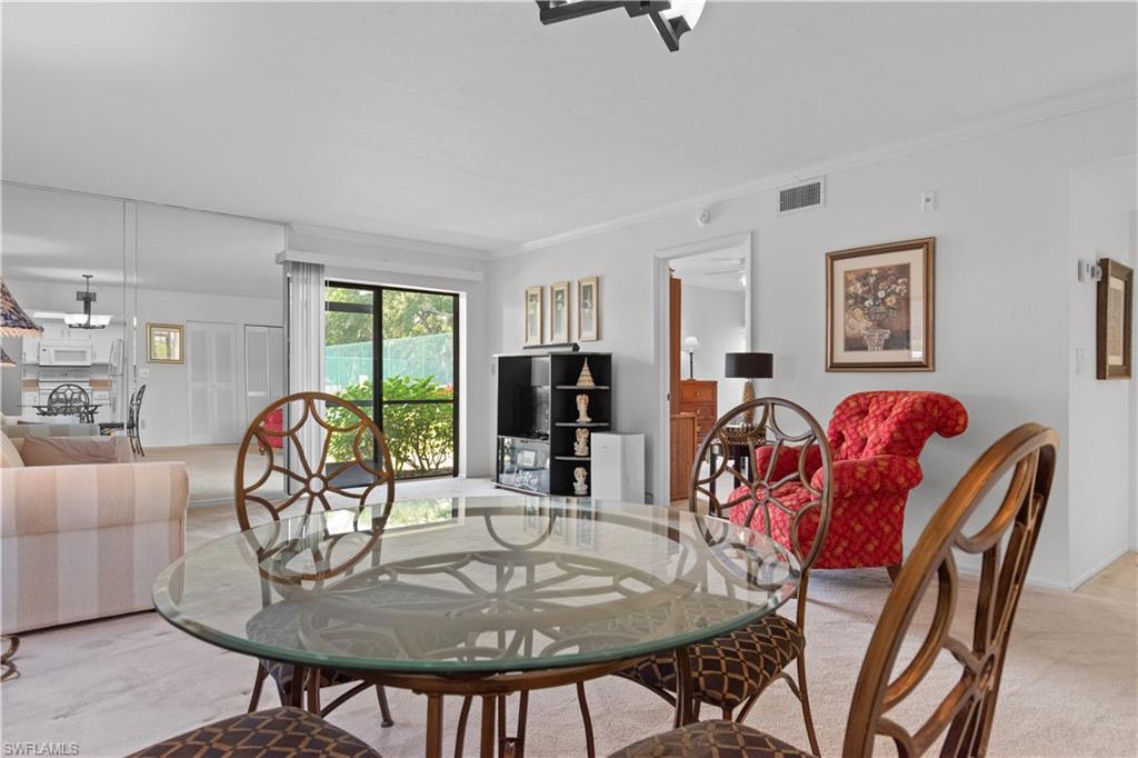 Carpeted living space with a glass-top dining table, a mirrored accent wall, and a sliding glass door