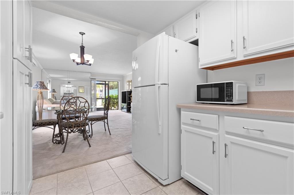 Kitchen with white cabinetry and tiled floor.