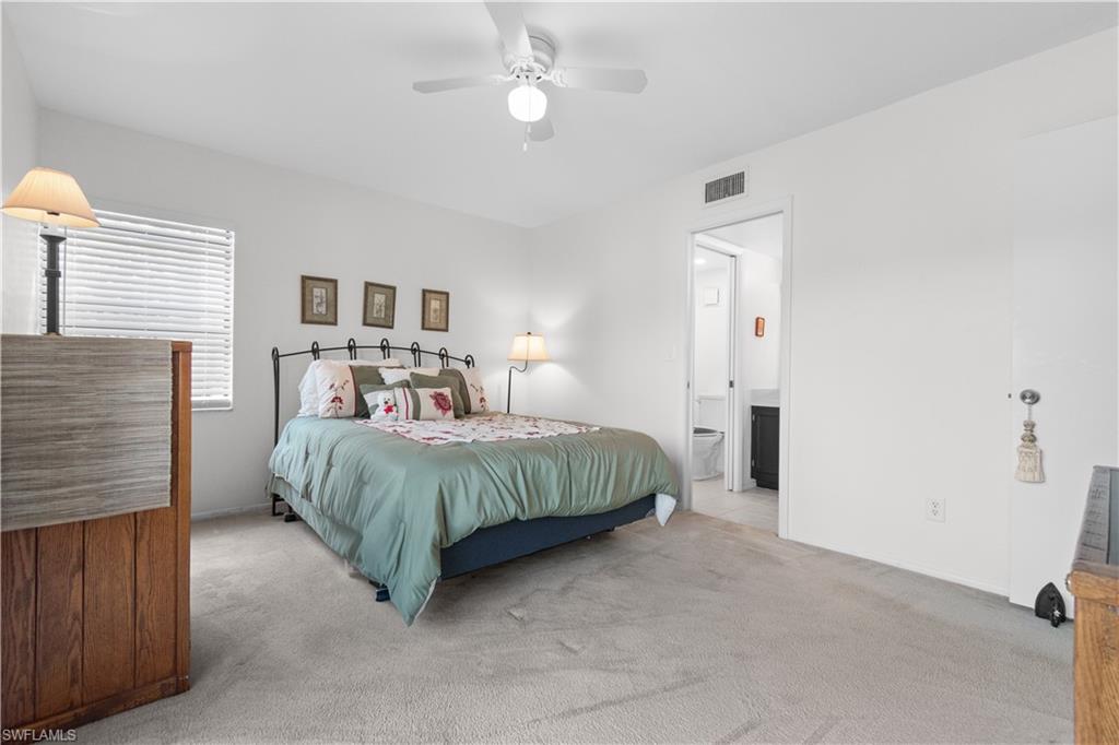Carpeted primary bedroom with a window featuring horizontal blinds and a ceiling fan
