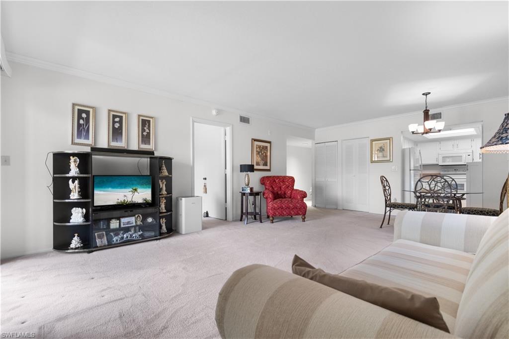 Open-concept living space featuring light-colored carpeting throughout