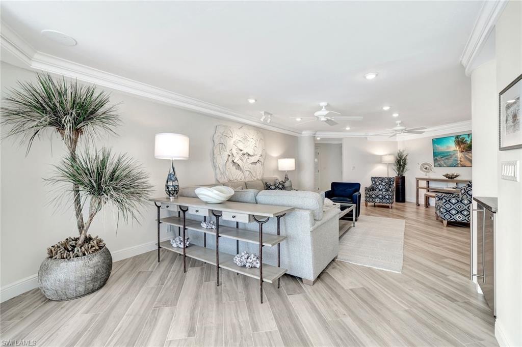 Living room with recessed lighting, ornamental molding, and light wood-style flooring