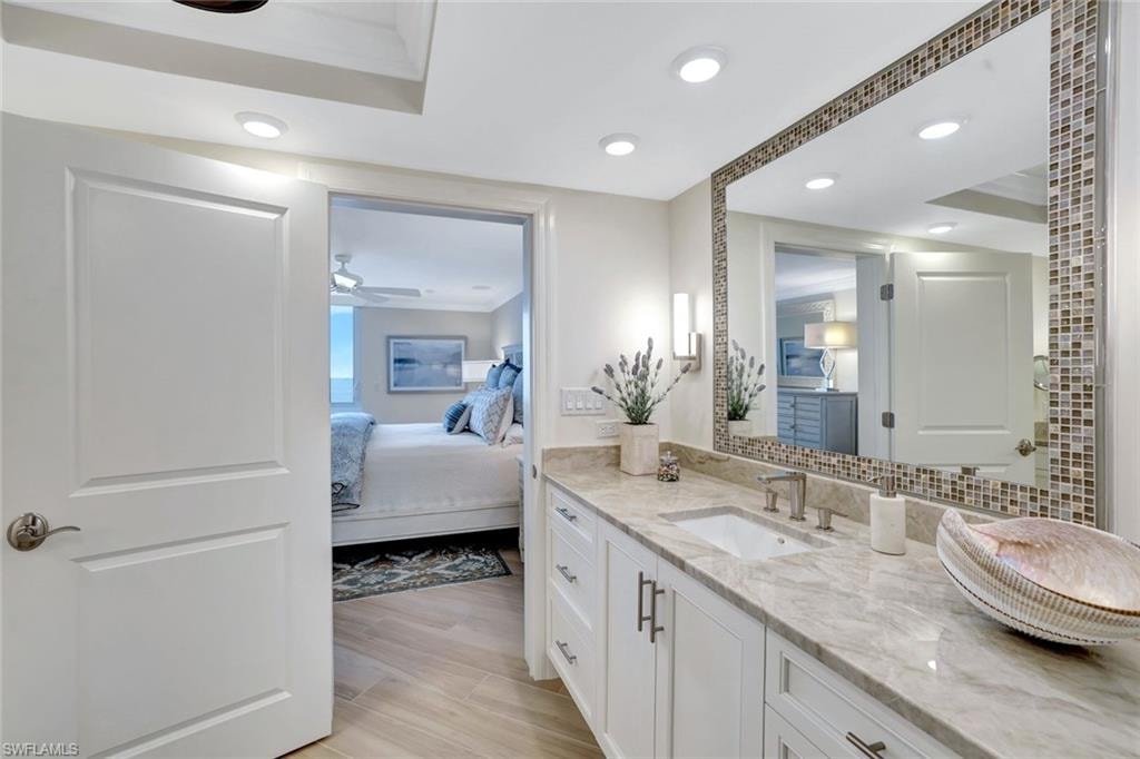 Ensuite bathroom with connected bathroom, ceiling fan, vanity, recessed lighting, and wood finished floors