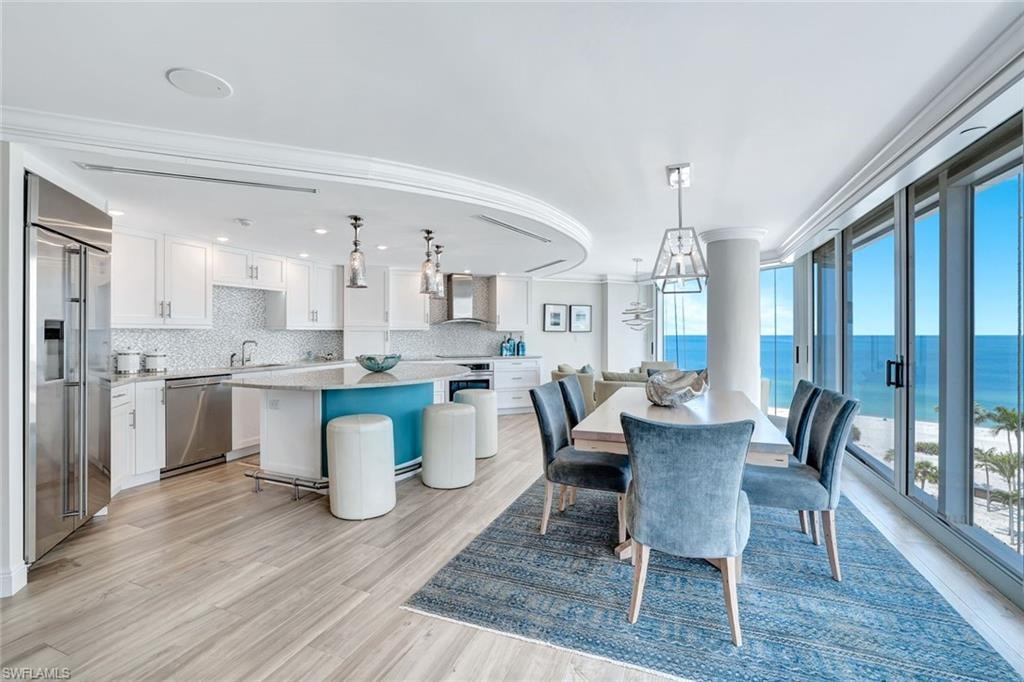 Dining area featuring crown molding, a water view, plenty of natural light, and light wood-type flooring
