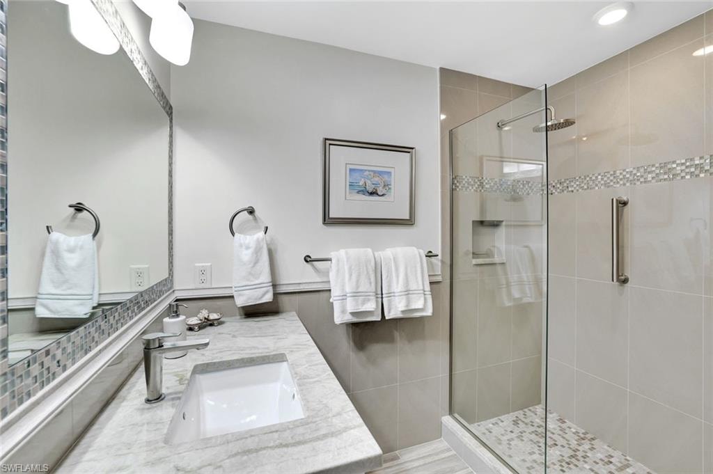 Full bathroom with recessed lighting, tile walls, a shower stall, and vanity