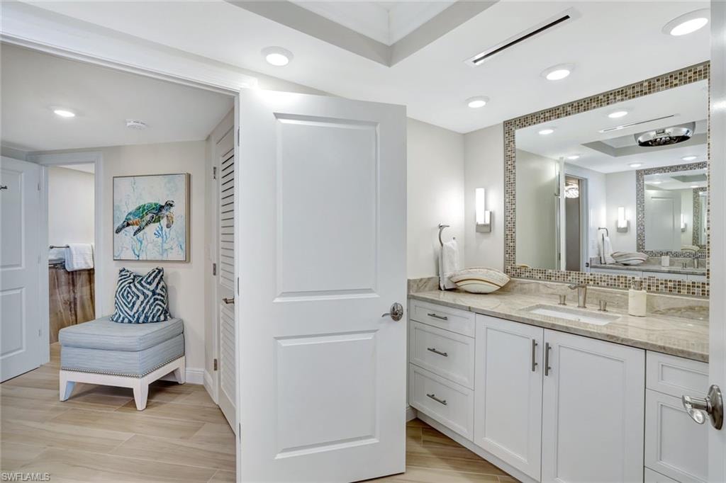 Bathroom with visible vents, vanity, baseboards, a raised ceiling, and backsplash