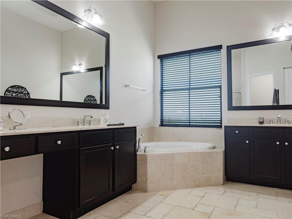 Bathroom with two vanities, a garden tub, and stone tile floors