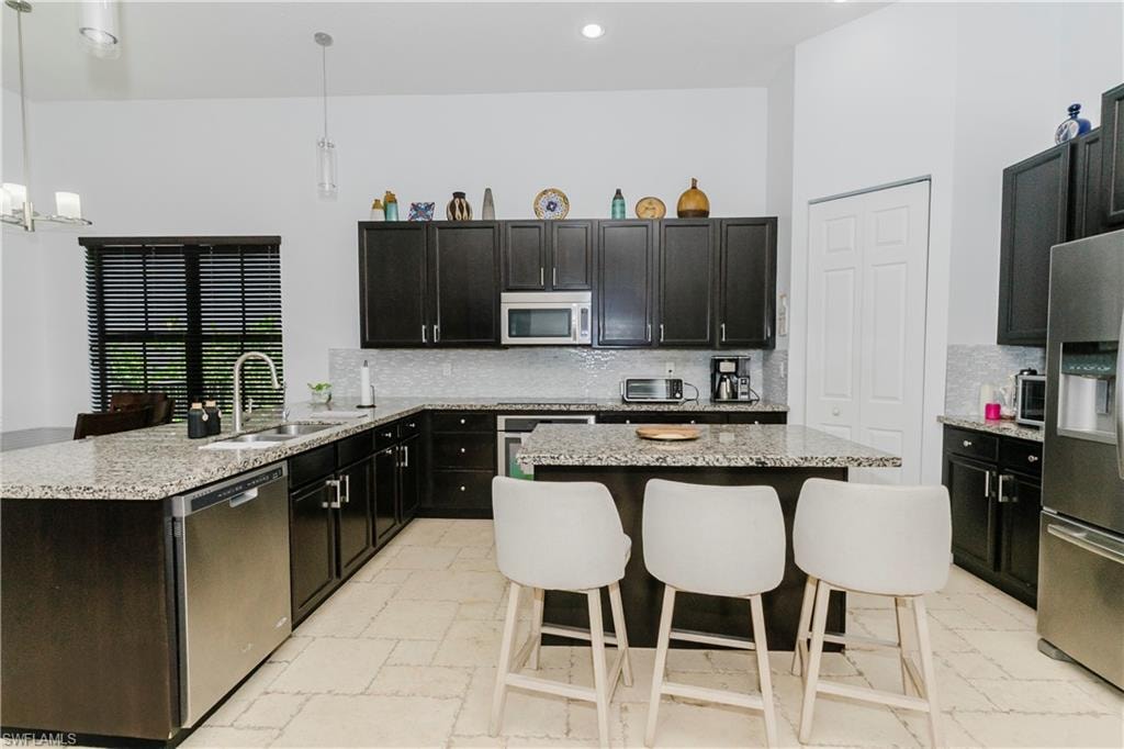 Kitchen featuring appliances with stainless steel finishes, decorative backsplash, a center island, a breakfast bar area, and a peninsula