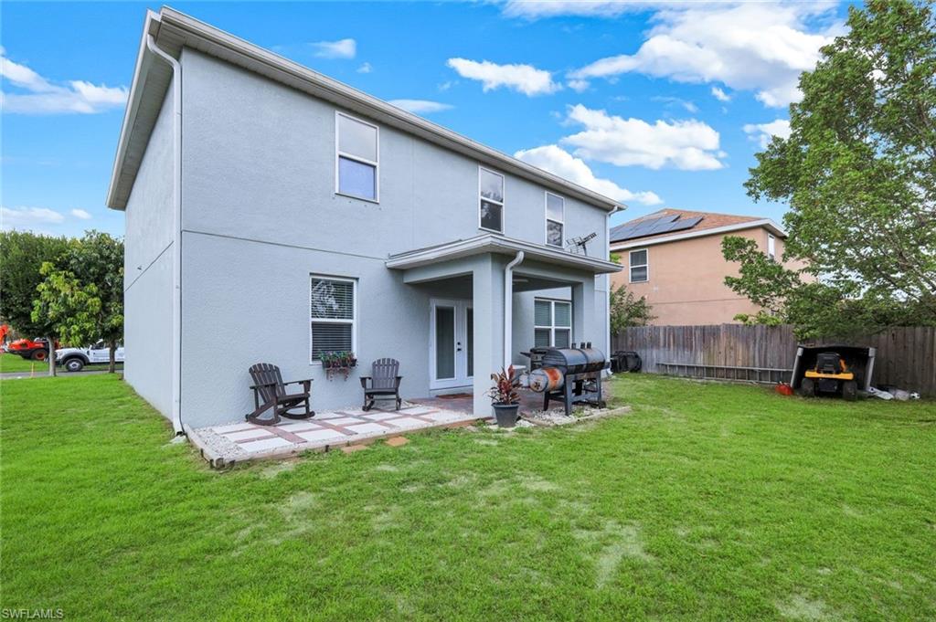 Spacious backyard featuring a covered patio with brick pavers, a substantial lawn area, and a privacy fence