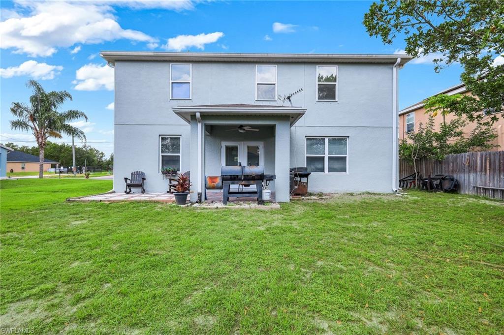 Expansive grass lawn with a two-story exterior featuring a covered patio