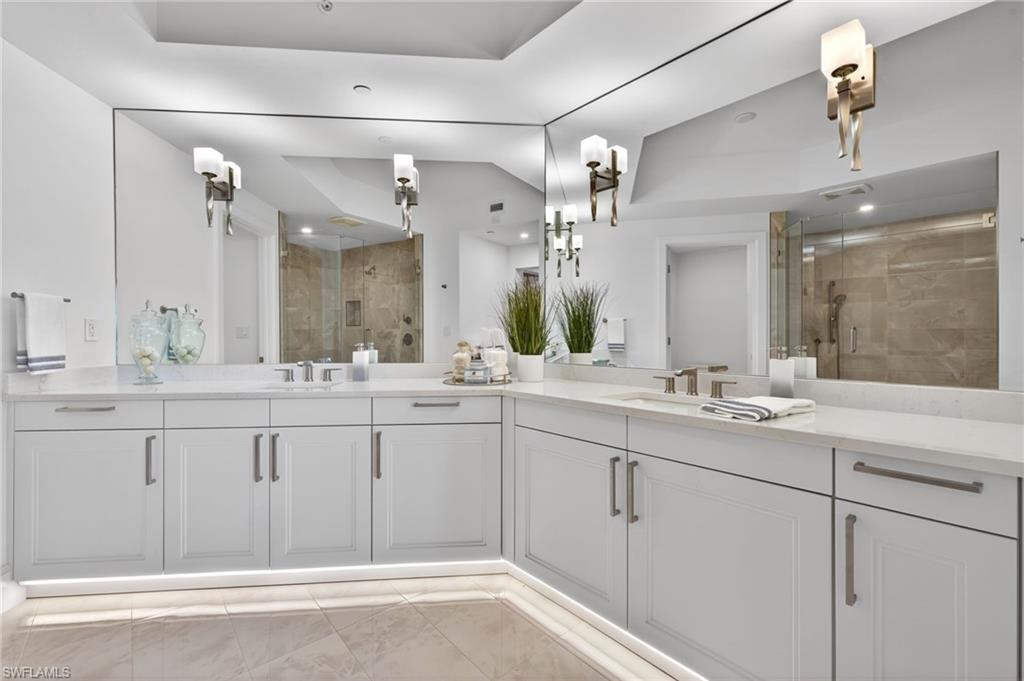 Master Suite Bathroom with a stall shower, double vanity, and light tile patterned floors, elegant sconce light fixtures